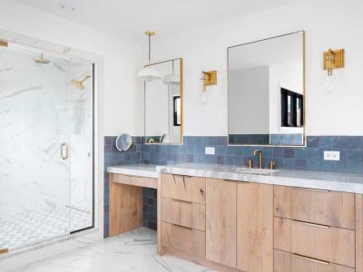 A Bathroom With A Wood Cabinet Gold Accents And A Marble Shower